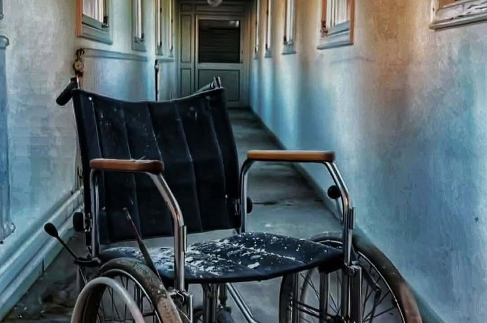 A wheelchair left behind in a blue-green corridor