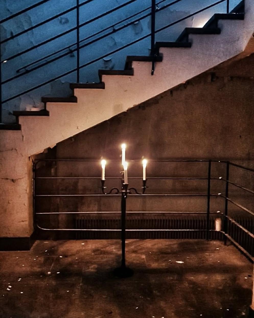 A lit candelabra in front of the stairs in a darkened stairwell